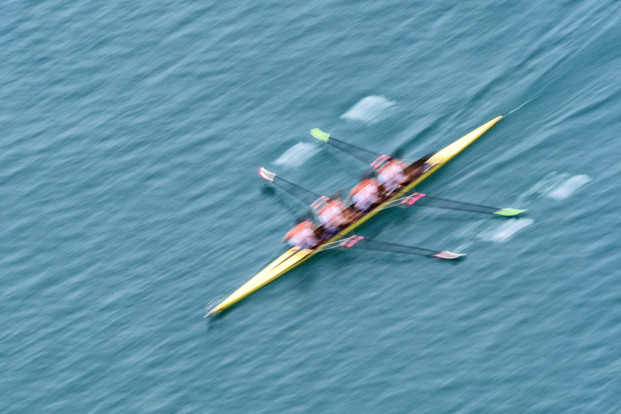 Upper view of quadruple scull rowing team on the water, blurred motion